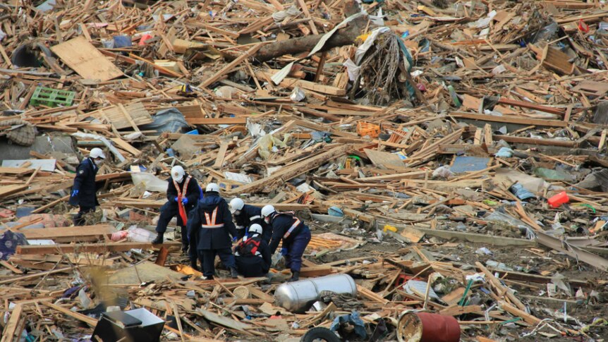 Emergency teams collect a body in Rikuzentakata