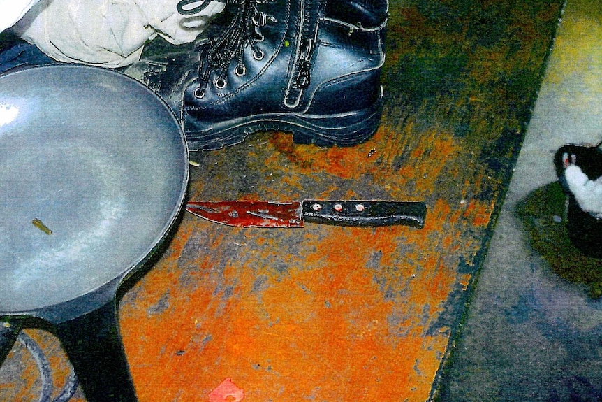Photo of a bloodied knife on a table with a saucepan and hiking boot next to it.