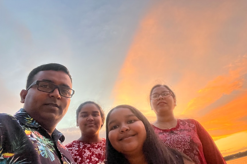 a young family taking a selfie by the sunset at a beach
