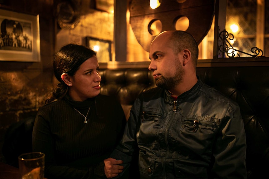 A woman and a man look each other in the eyes at a bar in Surry Hills