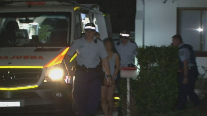 A handcuffed woman is led from a Riverwood home by police after a stabbing.