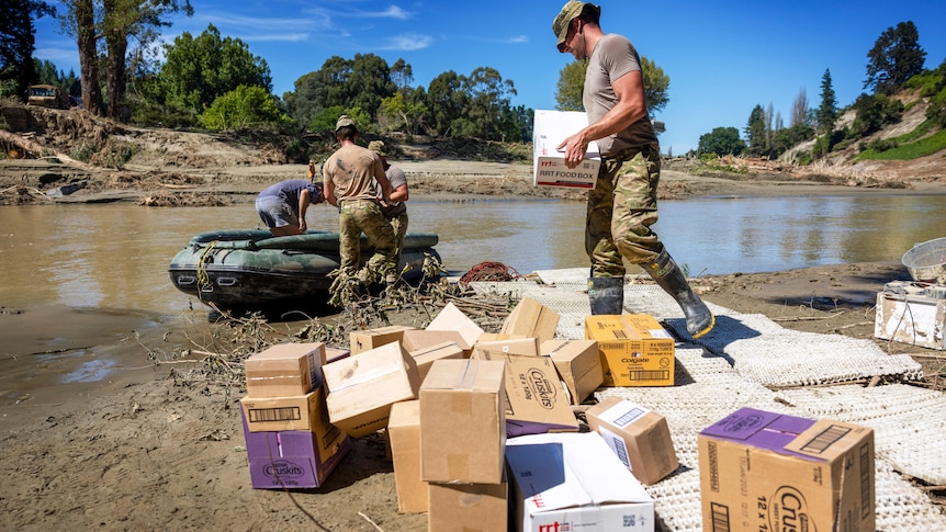 NZ defence force members carry supplies during the clean up after Cyclone Gabrielle hit