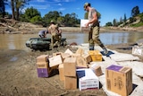 NZ defence force members carry supplies during the clean up after Cyclone Gabrielle hit
