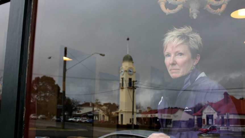 Claire looks through a cafe window