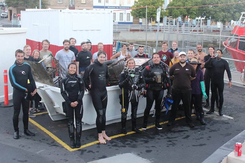 Divers pose with skip bin full of items retrieved from River Derwent.