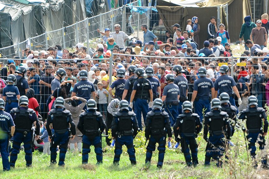 Riot police stand guard in front of a migrant reception centre in Hungary