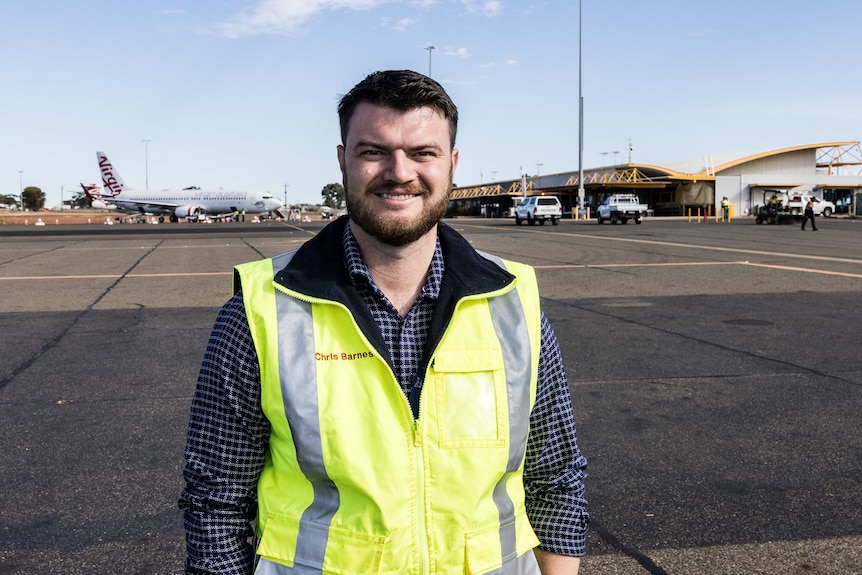 A man wearing high-vis on the tarmac at an airport.  
