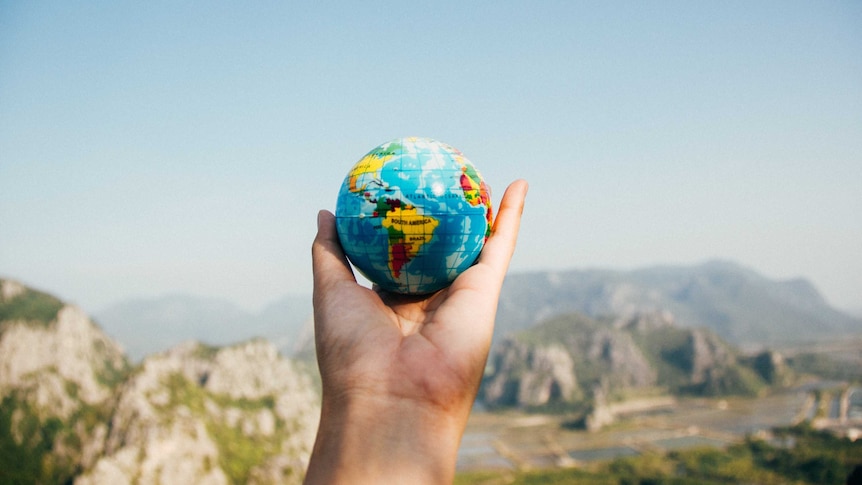 A person holds a palm-sized globe in their hand, for a story about the environmental impact of travel.