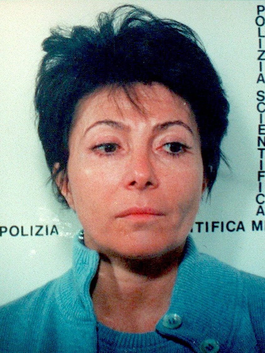 Patrizia Reggiani, a woman with cropped dark hair and thin eyebrows glances down past the camera