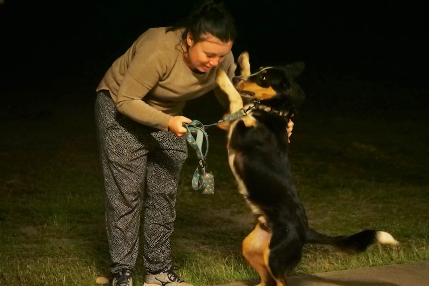 Sam Finch bending over, dog Bronson jumping up at her with both paws towards her face.