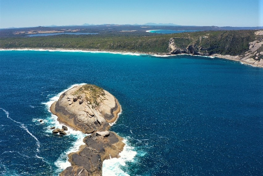 A drone shot of an island near the coastline.