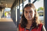 A young Aboriginal woman stands on the street