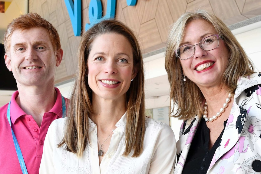 A man and two women standing in front of a sign that says "perkins".