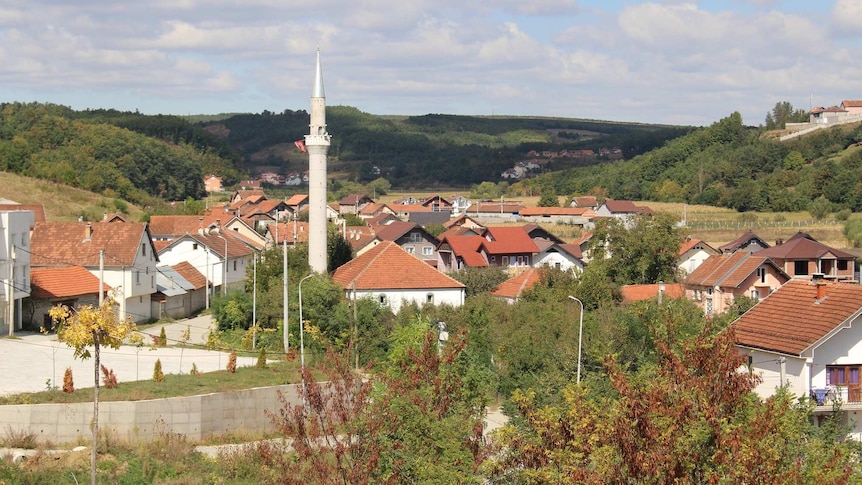 A picturesque village surrounded by hills with a prayer tower