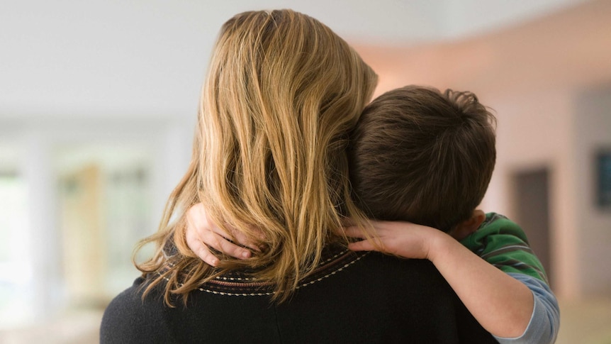 Boy rests his head on his mother's shoulder.