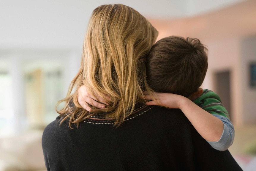 Boy rests his head on his mother's shoulder.