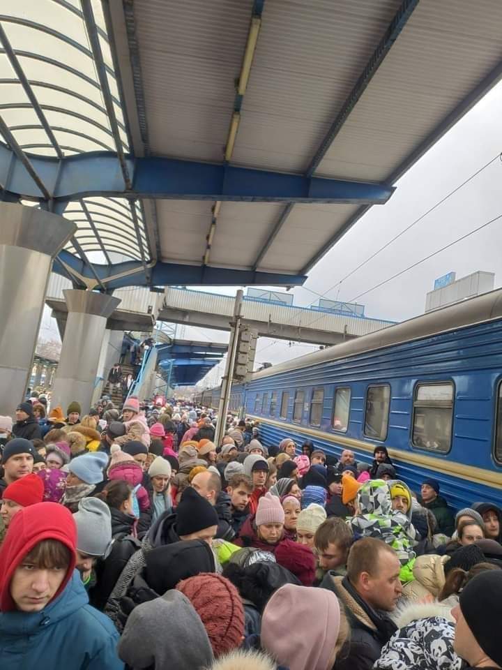 A throng of concerned people on a train platform, all rugged up against the cold