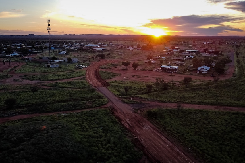 An aerial view of a remote community, as the sun sets on the horizon. 