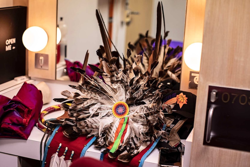 Eagle feathers arranged in circular shape with small colourful beaded design in centre sits on dressing room table.