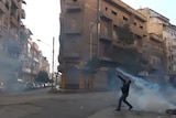 A protester throws a tear gas bomb in Homs