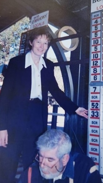 A woman and a man front of a board that has betting numbers on it. 
