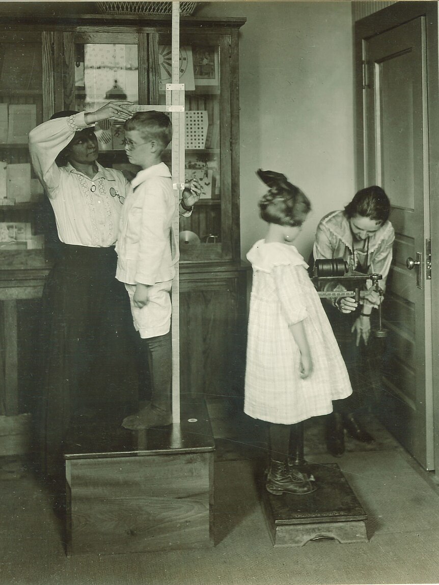 Historical photo of children getting their height and weight measured