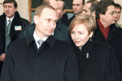Putin with his wife on the steps on a building.