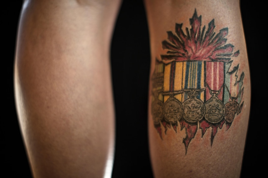 A tattoo of army medals on the back of a calf.