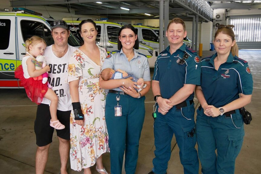 Two parents and their young children with paramedics