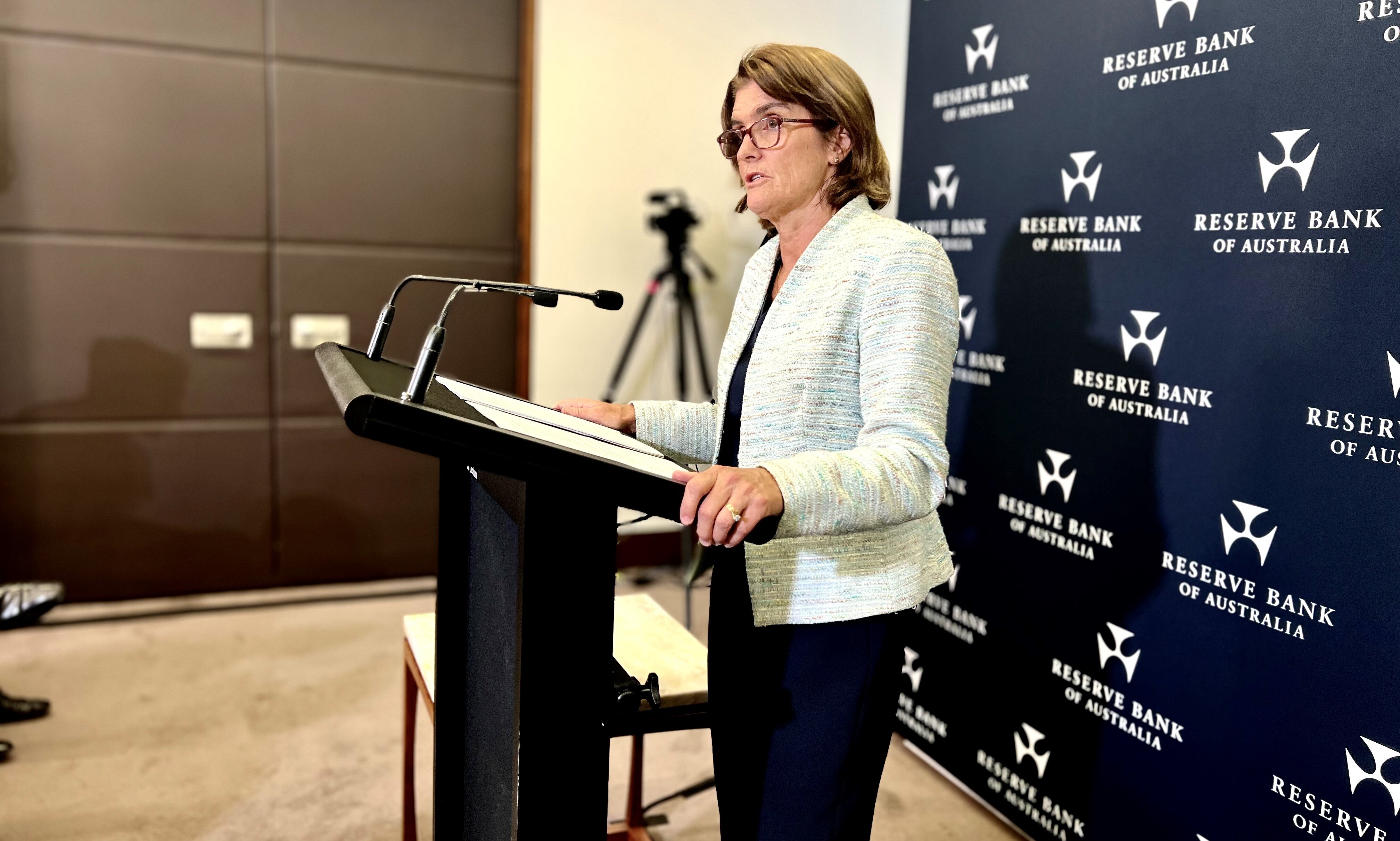 RBA governor Michele Bullock stands at a podium speaking at a press conference.