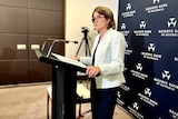 RBA governor Michele Bullock stands at a podium speaking at a press conference.