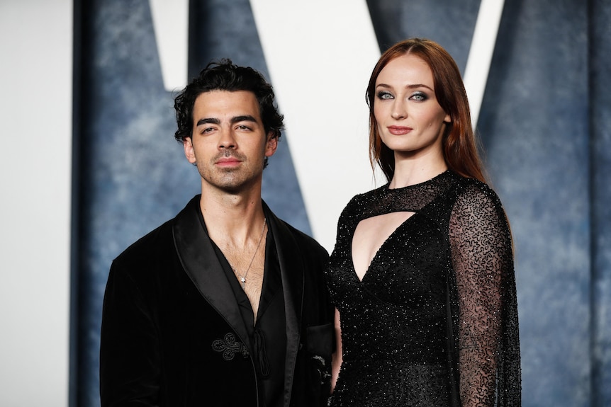Man and woman standing next to each other, all decked in black