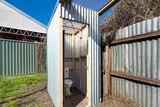 A corrugated iron structure with a toilet inside and clear pyrex roof. 