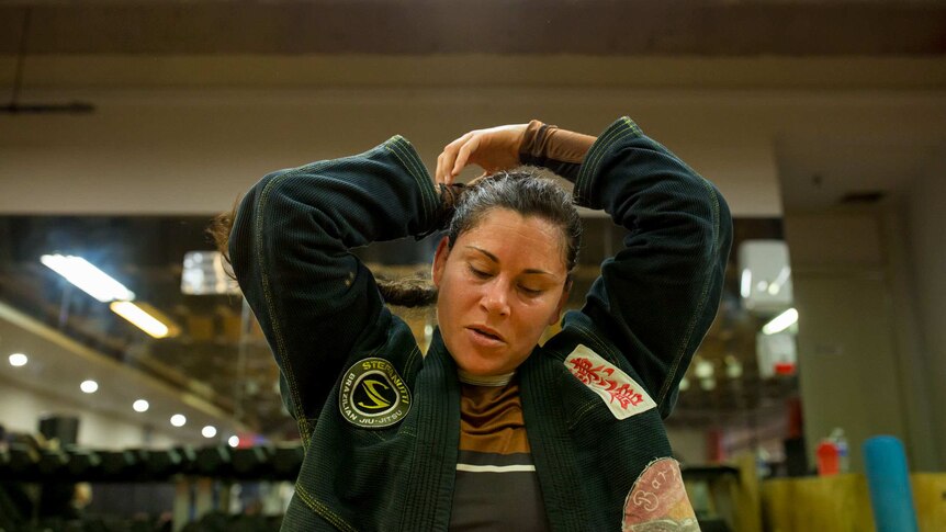 Thompson refastening her hair mid-training while dressed in a jiu-jitsu uniform.