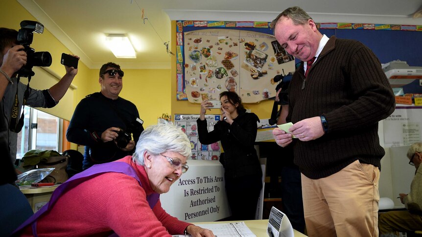 Barnaby Joyce smiles while waiting for his name to be marked on the electoral roll.