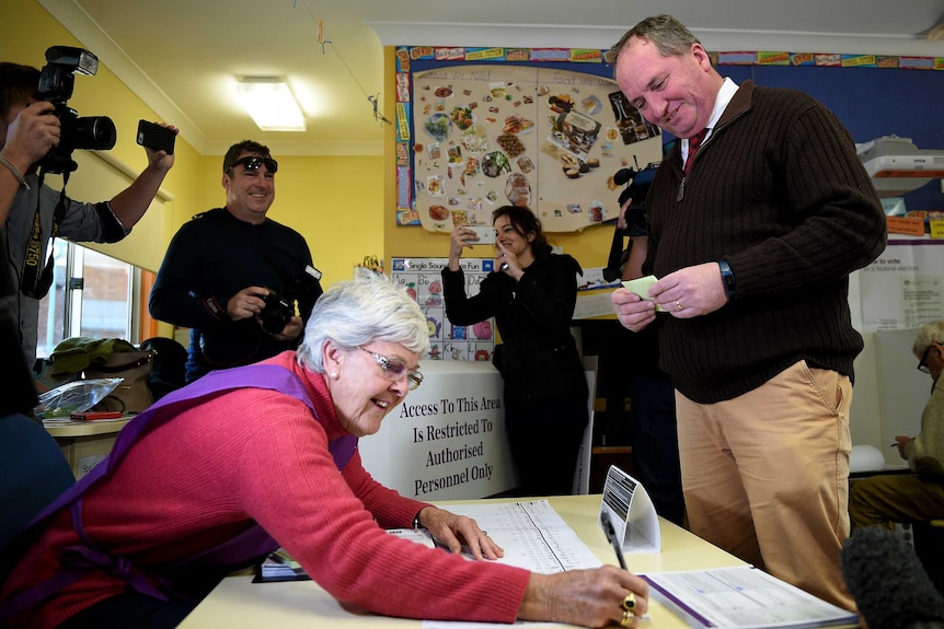 Barnaby Joyce smiles while waiting for his name to be marked on the electoral roll.