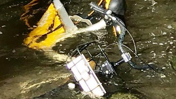 A yellow bike partially submerged in water next to a bluestone wall in Melbourne's Yarra River.