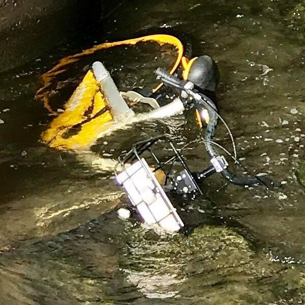 A yellow bike partially submerged in water next to a bluestone wall in Melbourne's Yarra River.