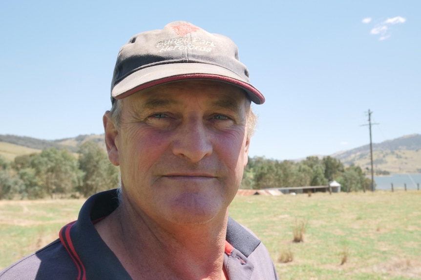 A man with a paddock and lake in the background.