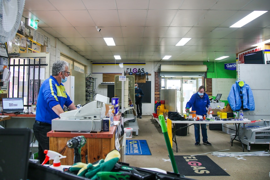 Two people pack up signage and stock in an empty store.