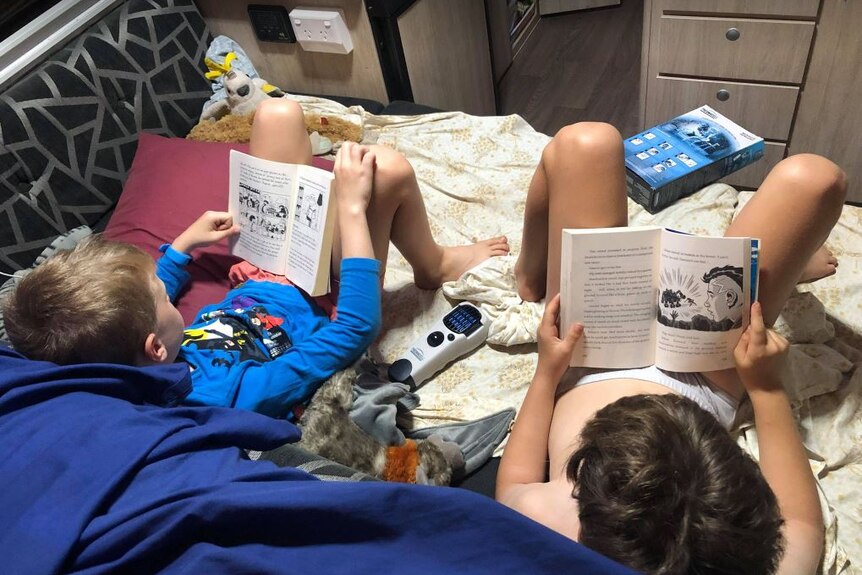 Young kids reading on a bed.