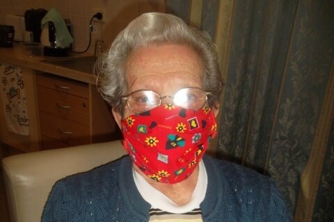 An elderly woman wearing a red face mask