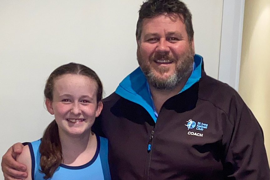Poppy Templeton poses for a photo in her netball uniform with her dad Rodney.