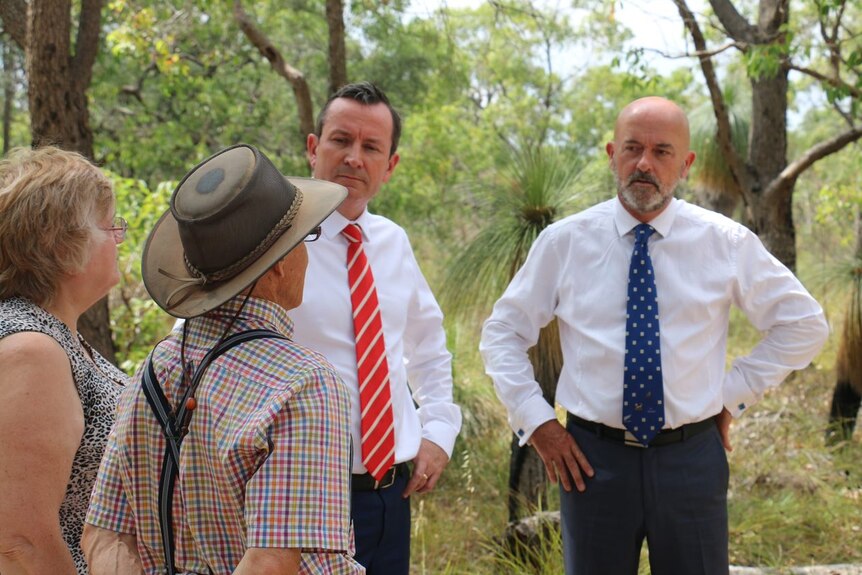 Labor candidate Hugh Jones and WA Premier Mark McGowan stand talking to a man and a woman in bushland.