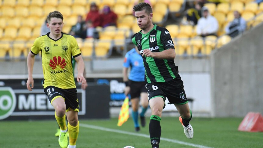 A Western United player dribbles the ball alongside a Wellington Phoenix opponent in the A-League.