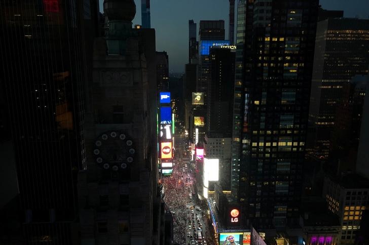 Some elements of the Times Square display are dark as a blackout hits the city. People are seen milling below as the sky is dark