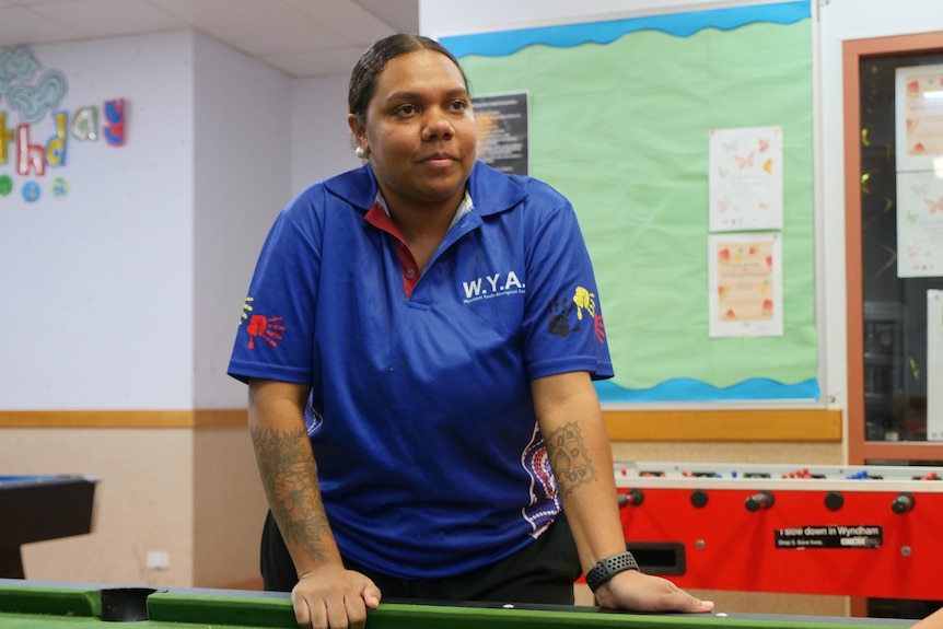 An Indigenous lady in her early twenties leans over a pool table