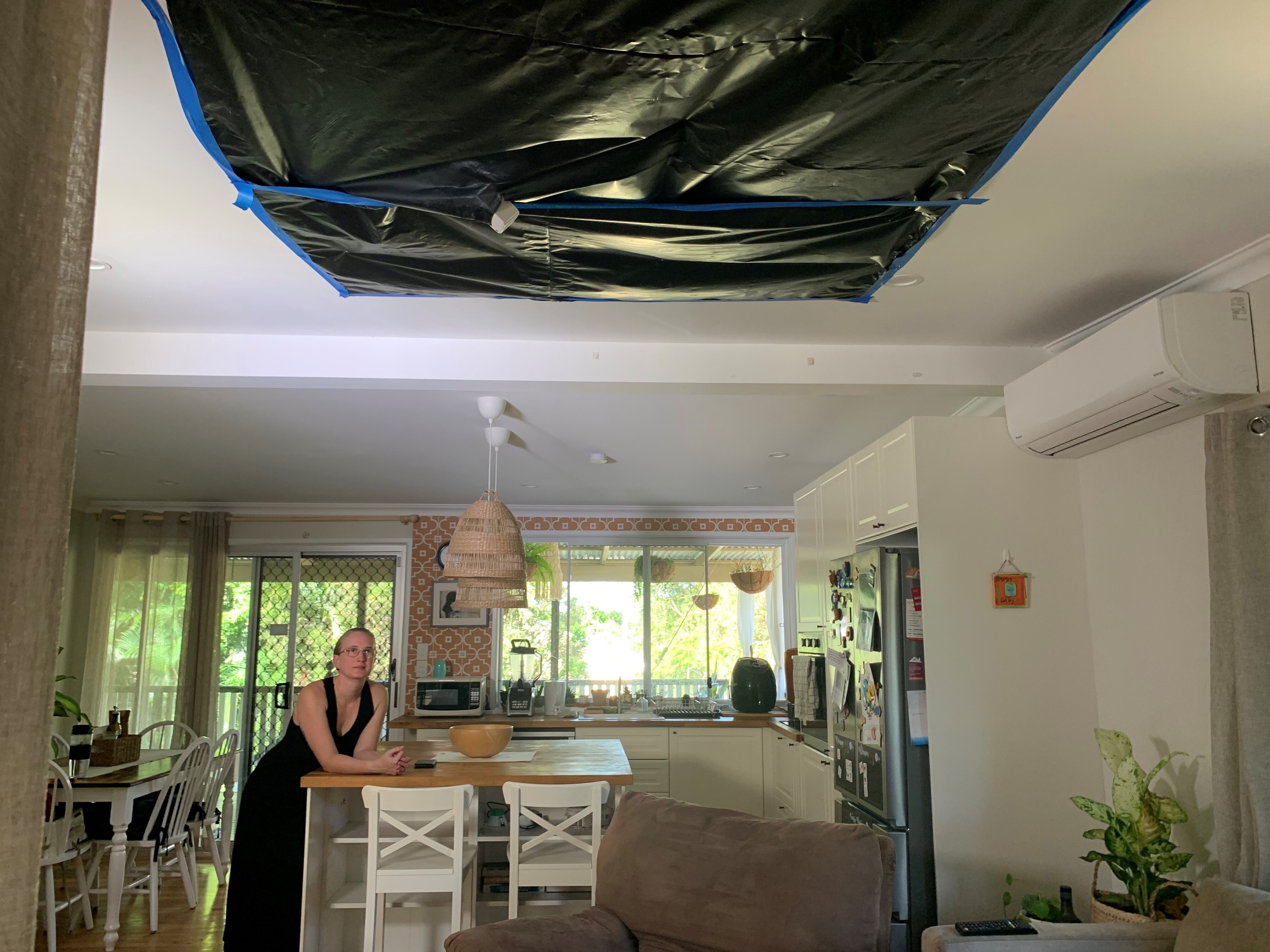 a woman in a house looking up at a ceiling covered in building tarp
