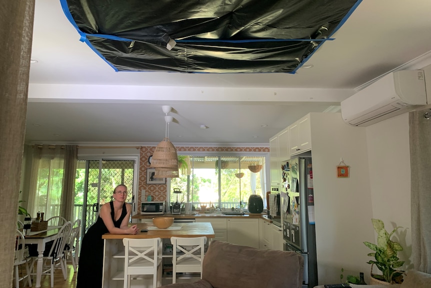 a woman in a house looking up at a ceiling covered in building tarp