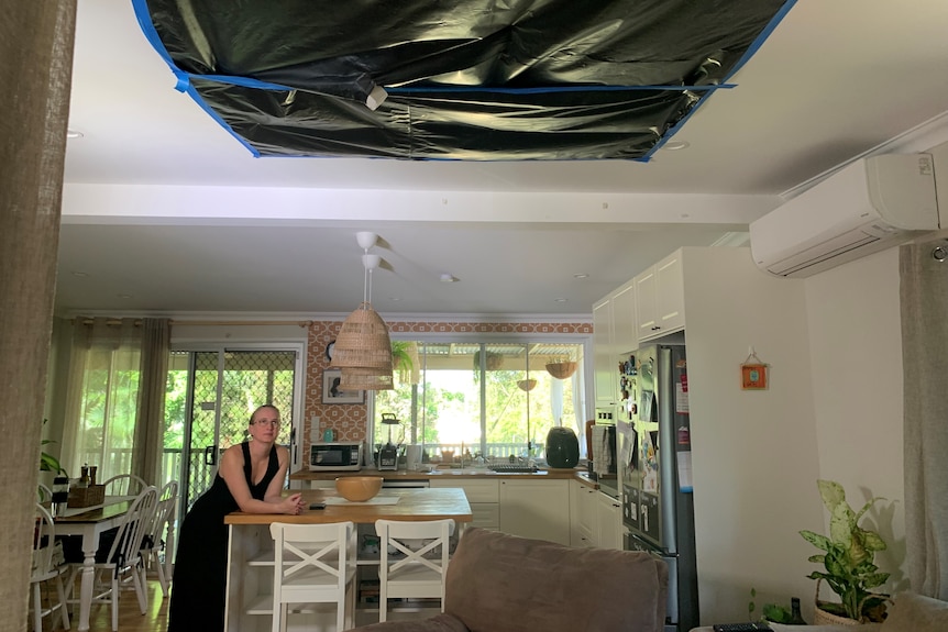 una mujer en una casa mirando hacia un techo cubierto de lona de construcción